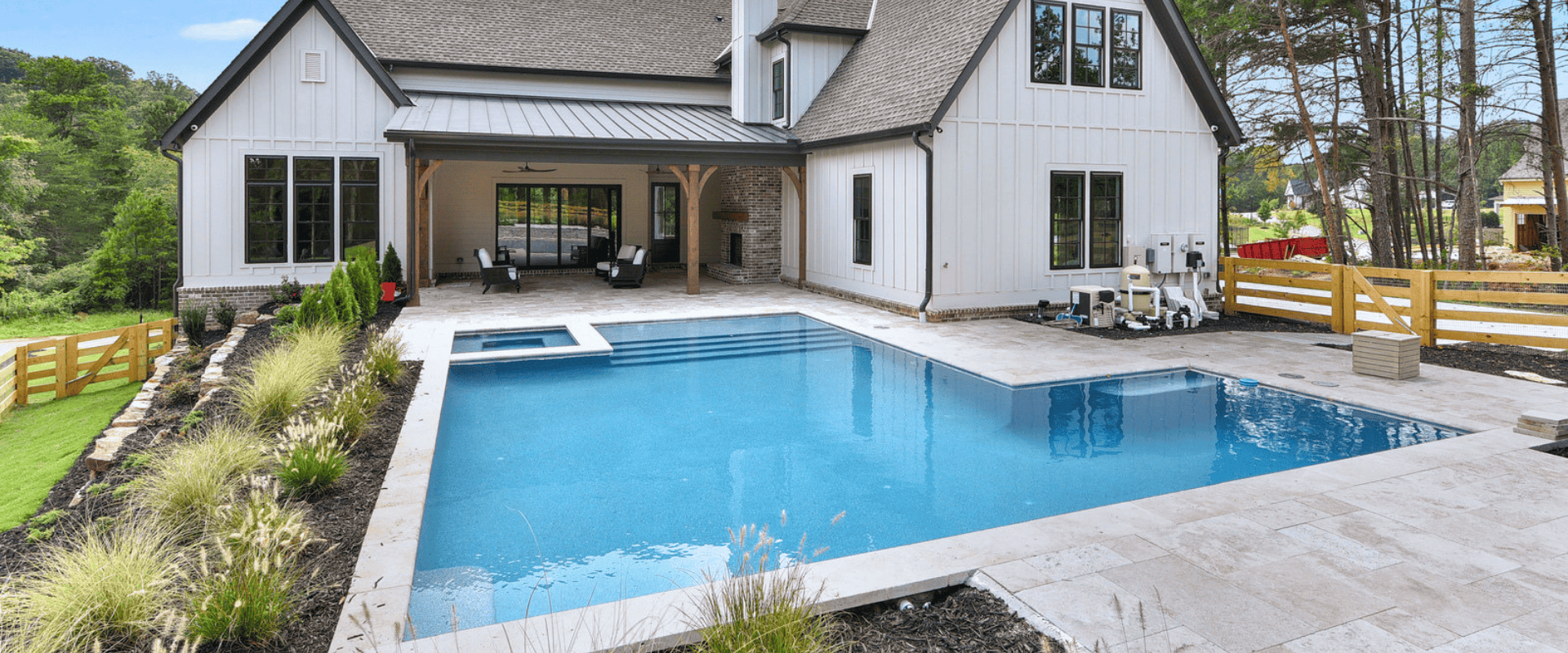 Custom L-shaped geometric pool with integrated spa and paver deck behind a modern farmhouse.